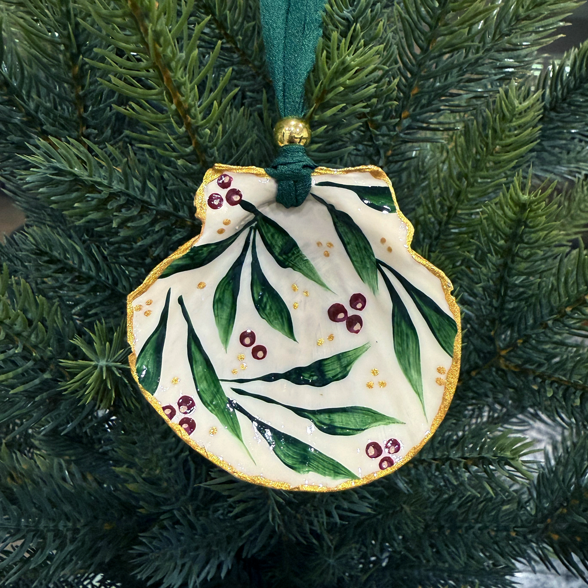 Decorative ornament with green leaves and red berries on a tree branch