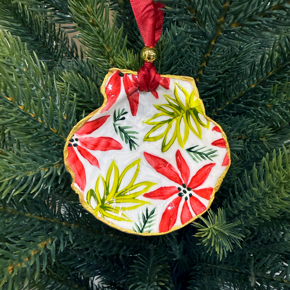 Decorative Christmas ornament with red and green floral design on a tree.